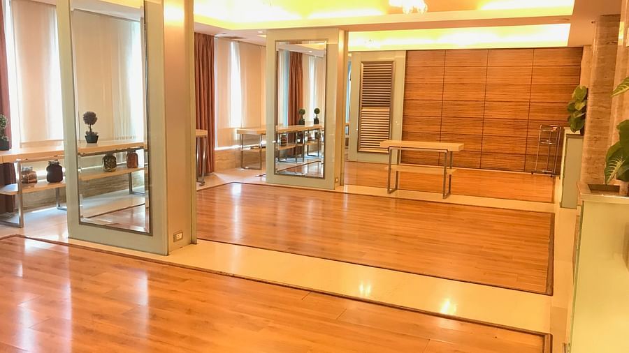 Spacious wooden-floor banquet hall with large mirrors and ceiling lights, ideal for events or gatherings at Mirage Hotel, Mumbai.