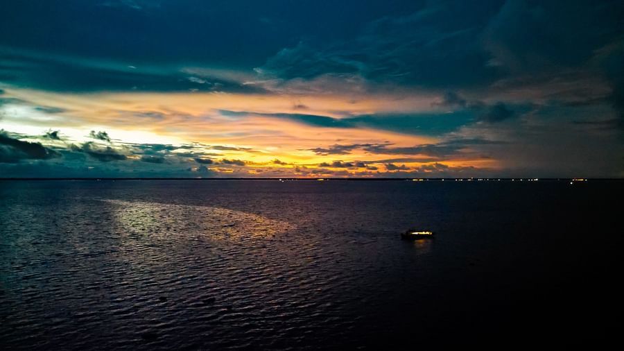 Rhythm Kumarakom - A sunset aerial view of the river and the sky with a houseboat on the river