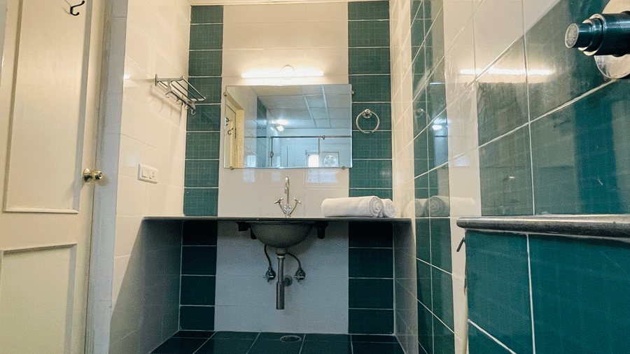 Bathroom with teal mosaic tiles, a wall-mounted sink, and a mirror at Sanctum Suites Indiranagar, Bangalore.