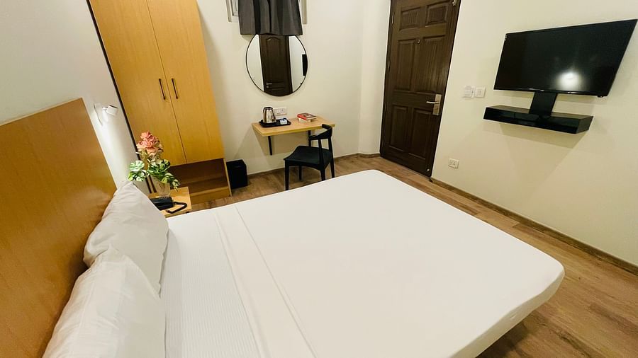 Image of a double bed a TV and a cupboard at Sanctum Suites Richmond Road Bangalore