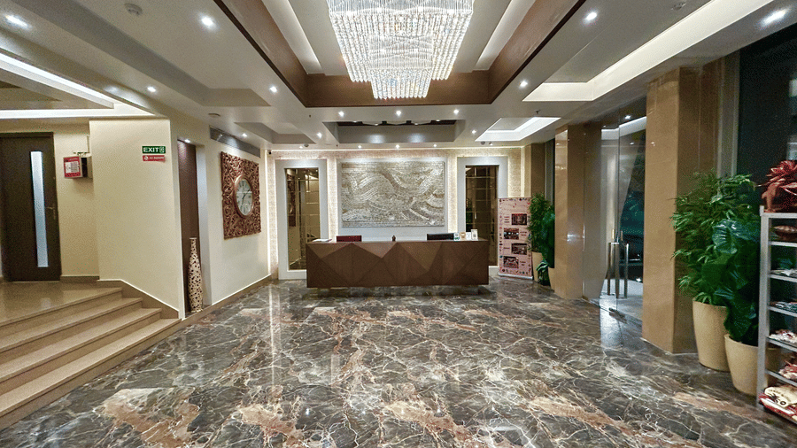 A lobby with a polished marble floor, a reception desk, and a large central chandelier