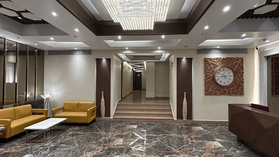 IMG 1848A hotel lobby featuring a marble floor, two yellow sofas, a large chandelier, and a clock on the wall
