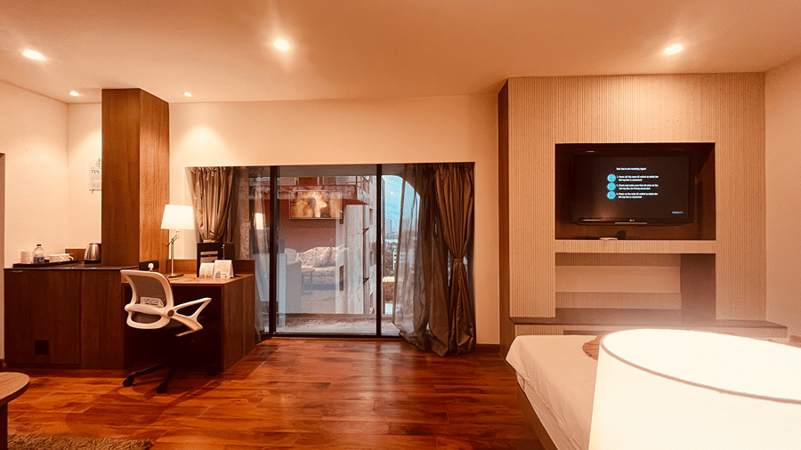 An expansive area beside the plush double bed with wooden flooring with a huge french window in the far at Senses Hotel.