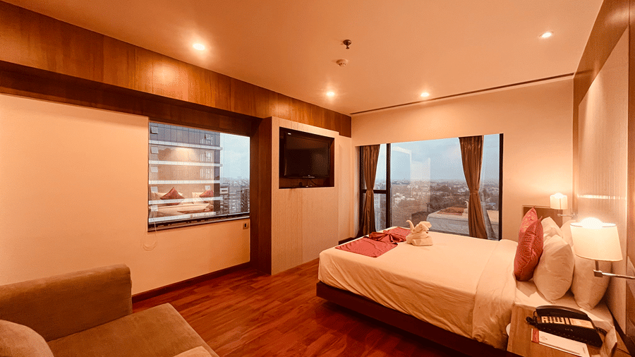 A wide angle shot of the bedroom of the Premier Smart Suite featuring a comfortable double bed and a wall mounted television opposite to it at the Senses Hotel.