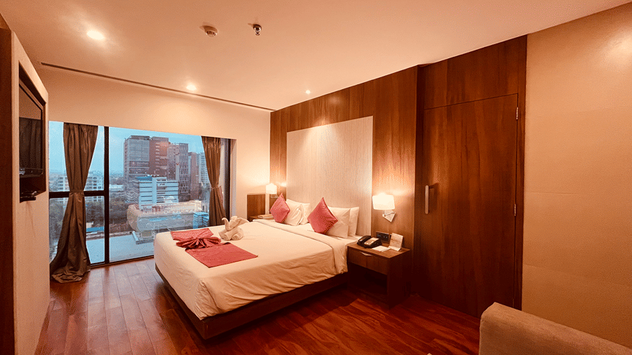 A wide angle shot of the Premier Smart Suite featuring a plush double bed and huge french windows in the far end of the room at the Senses Hotel.