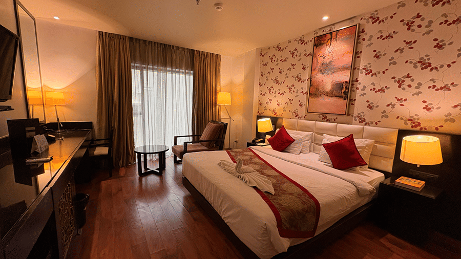 A wide angle shot of the Executive Room with warm lighting featuring a double bed and a beautiful wallpaper on the master wall - Senses Hotel