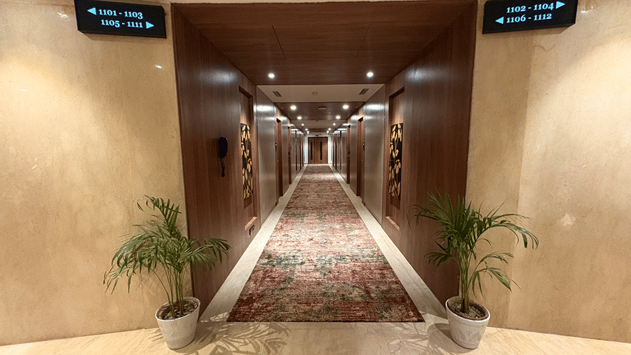 The well-lit and carpeted hotel corridor at Senses Hotel with electronically displayed hotel room numbers