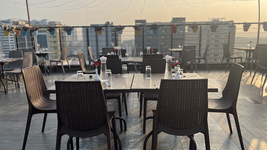 Rooftop dining setup with chairs and tables overlooking a scenic view.