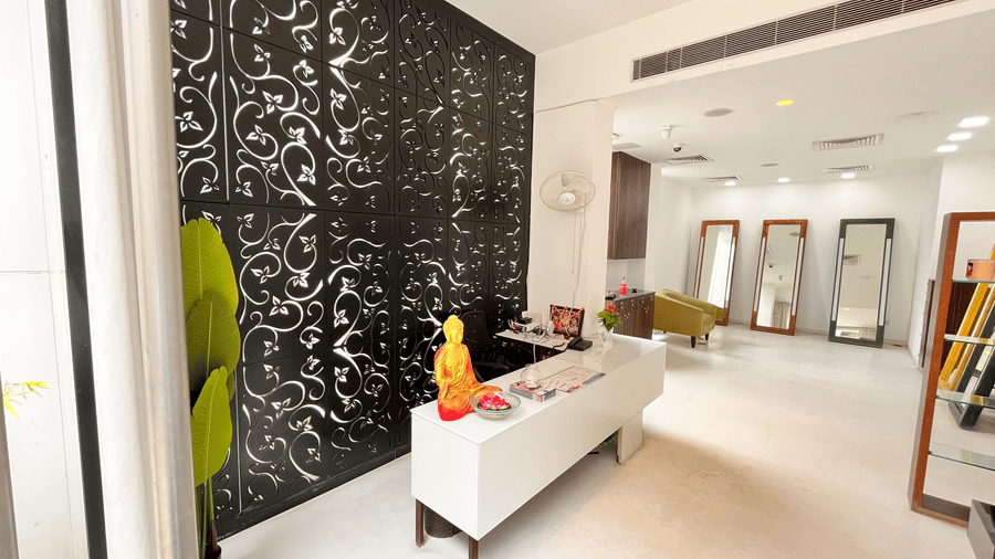 A bright and stylish spa reception area with a modern white counter, decorative black patterned wall and indoor plant atSprings Hotel & Spa, Bangalore