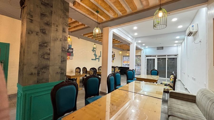 Spacious restaurant with wooden tables, cushioned chairs, and decorative lighting at Sumitel Premier Inn.