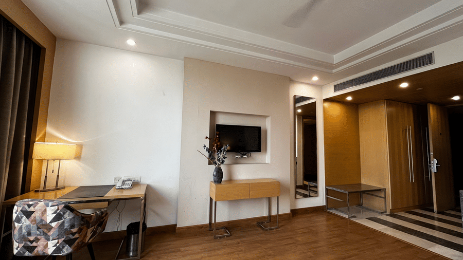 Room interior with writing desk, television, seating space and entry area at The Conway, Meerut
