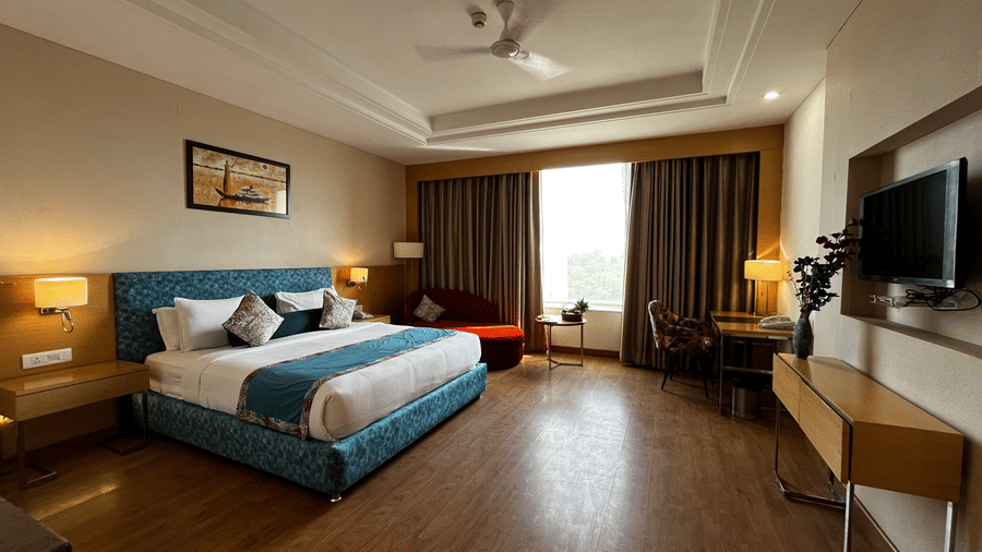 Guest room with king bed, seating space, television and window view at The Conway, Meerut