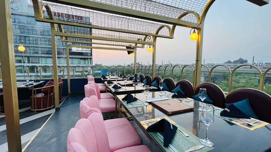 An image of a rooftop Restaurant Themis Barbecue House NSP Pitampura featuring chairs and a large table 