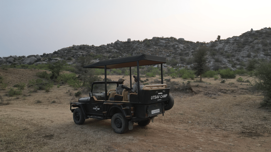 An image of a jeep parked amidst the rocky mountains - Utsav Camp Sariska