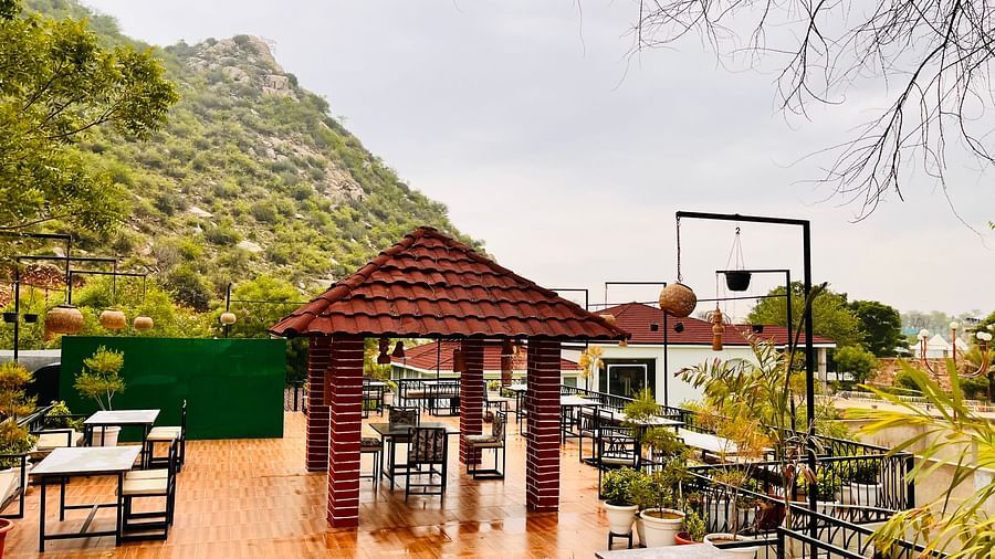 An outdoor dining area with tables and chairs surrounded by greenery at Valley by Grassfield.
