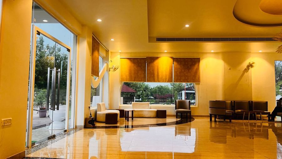 A warmly lighted reception area with sofas and chairs in the corner at Valley by Grassfield.