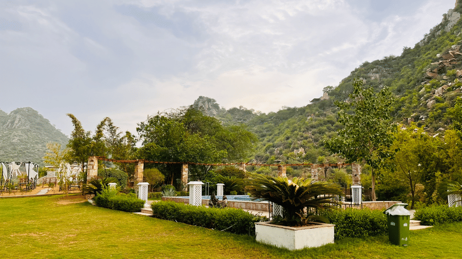Plant-filled grounds with mountain views at Valley by Grassfield, a resort in Jaipur.
