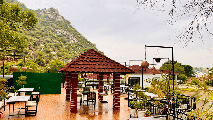 Outdoor dining tables surrounded by greenery at Valley by Grassfield, a resort in Jaipur.