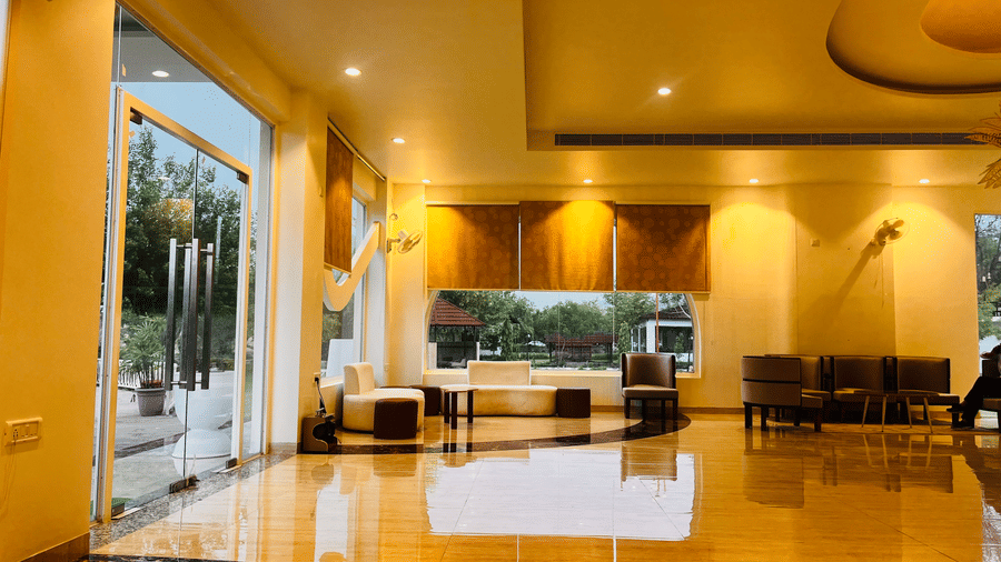 Warmly lit reception lounge with sofas at Valley by Grassfield, a resort in Jaipur.