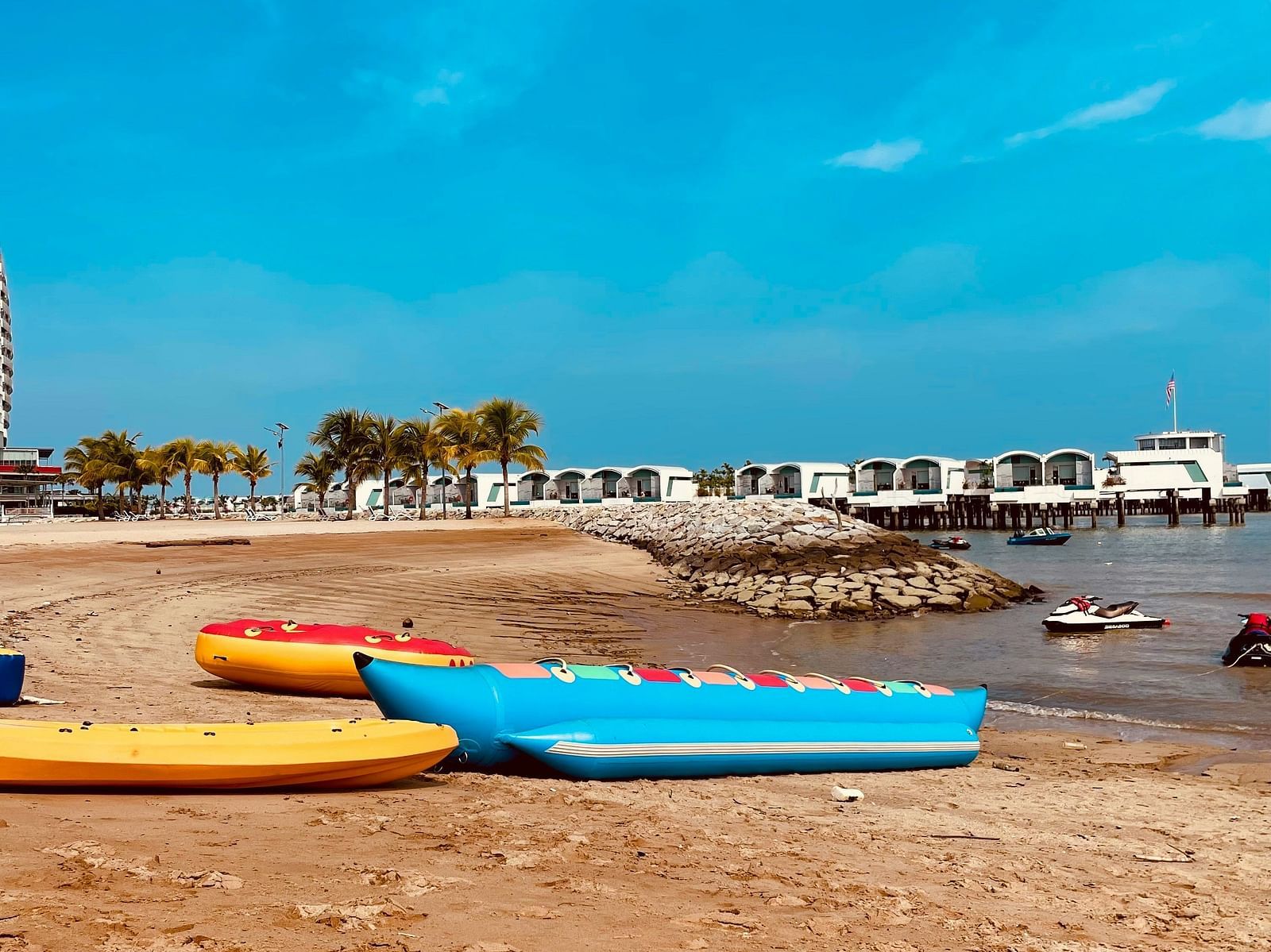 A few inflatable boats parked on the beach with a Banana Boat also in view.