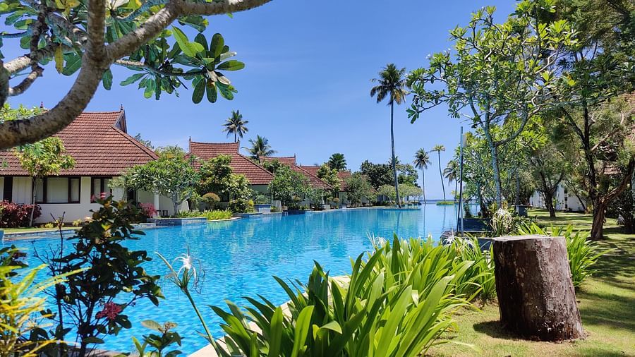 an image of a swimming pool with rooms and trees in view - Rhythm Kumarakom