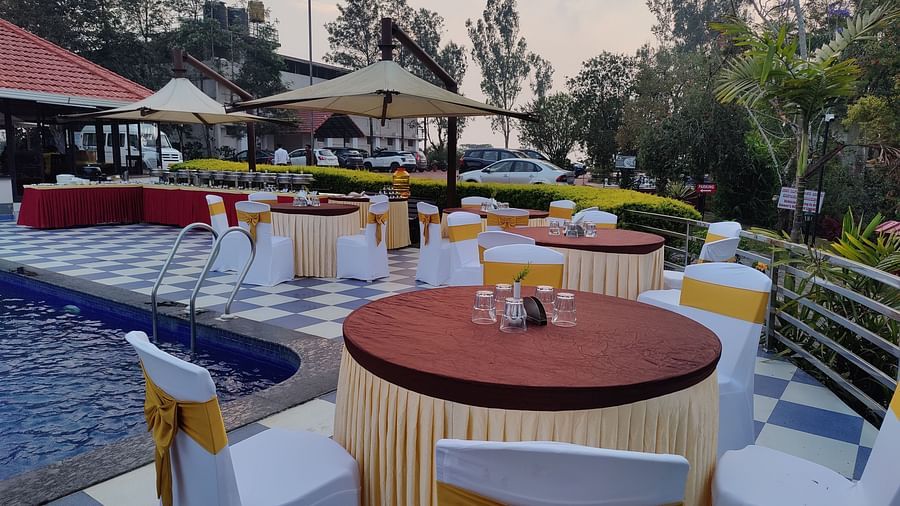 Outdoor dining area with round tables and umbrellas | Open Deck | Woodstock Resorts, Coorg