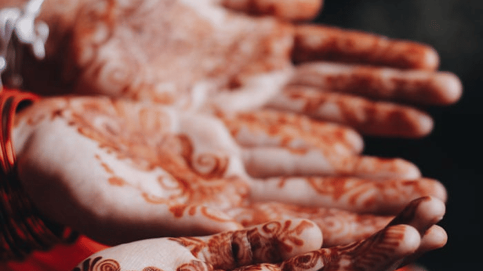 Close-up of local women showing their hands decorated with festive red henna paste during a cultural celebration in Bhaktapur, Nepal.