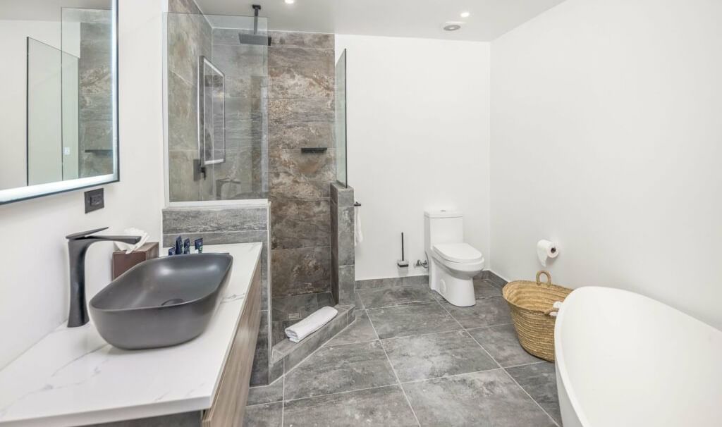  A contemporary bathroom featuring a walk-in shower with a glass screen, and a modern vessel sink - Tamarind Hills Resort and Villas - Antigua