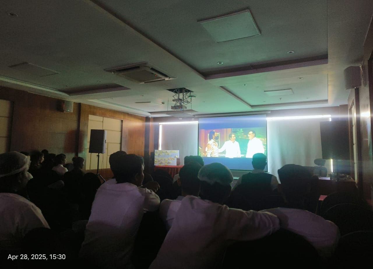 People gathered in a room watching a movie projected onto a large screen - Bamboo Saa