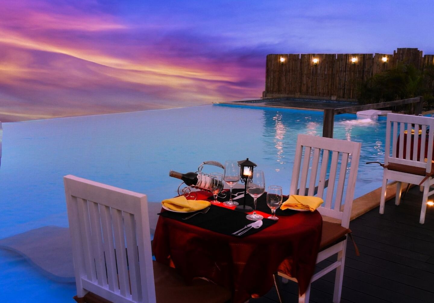 Outdoor dining setup beside an infinity pool during sunset at Polo Resort Cherrapunjee.