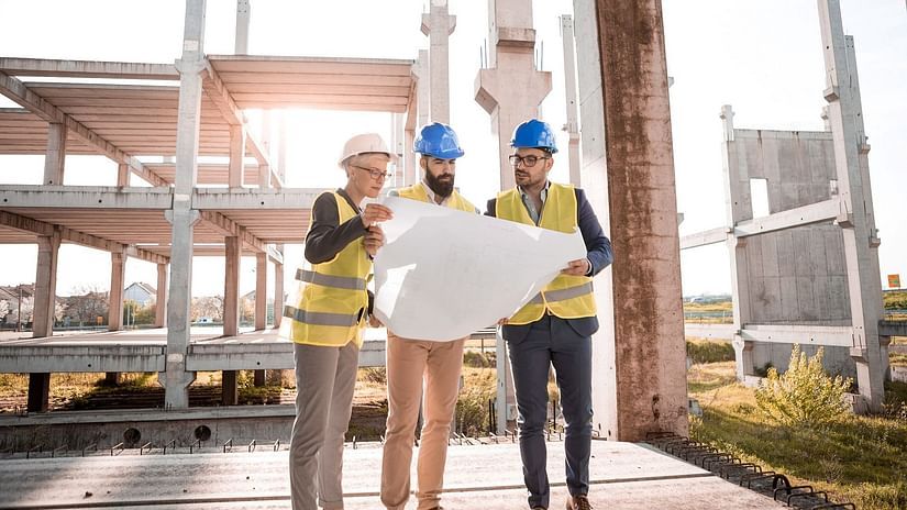 Three architects discussing a plan and holding a chart