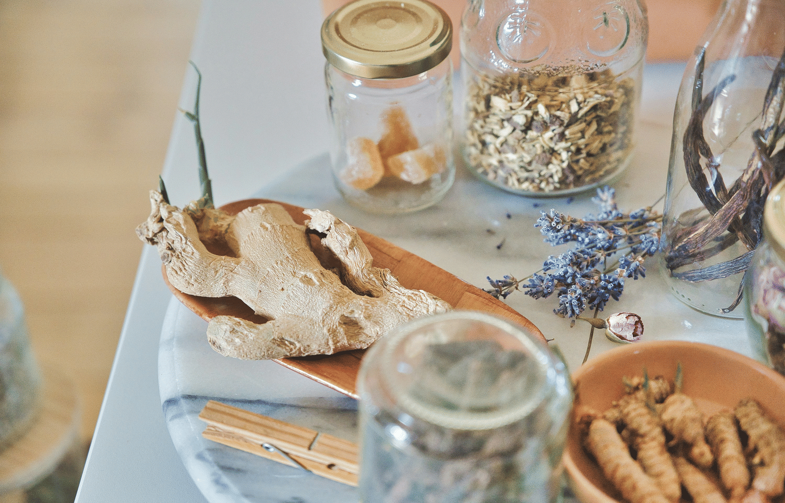 A selection of jars and bowls containing dried herbs, spices, and roots arranged for a wellness treatment.