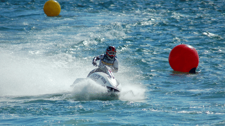 a person jet skiing on a waterbody with floating devices behind him 
