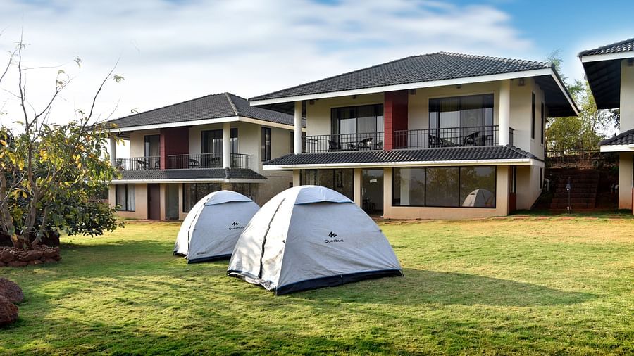 Accommodations at Forest Escapes Koyna include modern buildings and tents set up on the lawn.