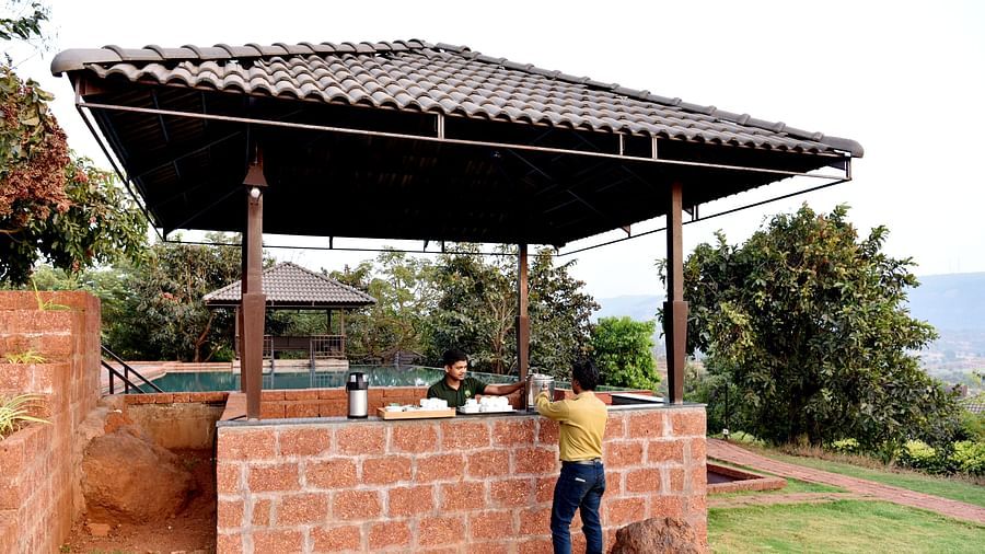 An outdoor barbecue setup at Forest Escapes Koyna with a covered area and people preparing food.