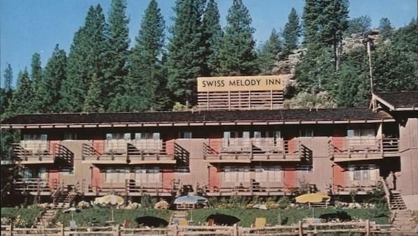 Exterior of Narrow Gauge Inn with a lawn in the front, and trees canopying the entire Inn.