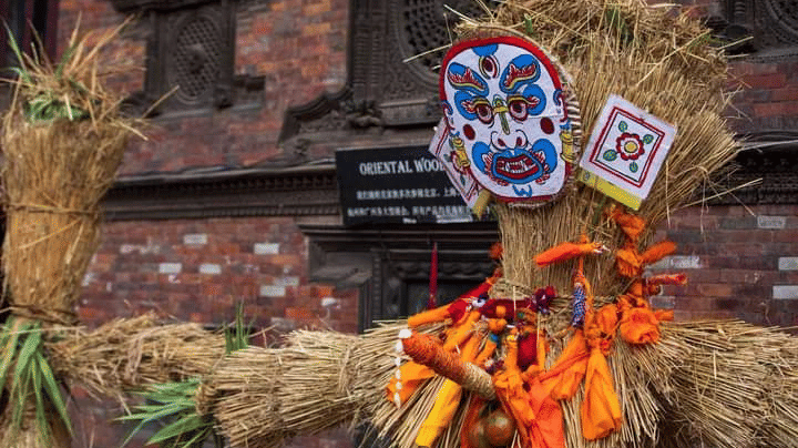 Close-up of a handmade straw effigy with a painted scary mask symbolizing the demon Ghantakarna outside a brick house in Bhaktapur, Nepal.