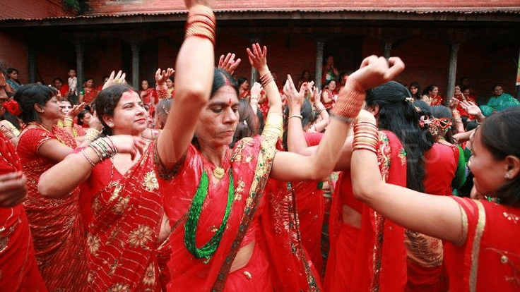 Group of local Newar women dancing with hands raised during the annual Teej festival in a historic courtyard in Bhaktapur, Nepal.