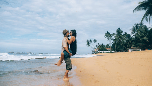 couple in beach surrounded by trees and clear view sky.