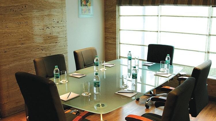 Image of a meeting room at our hotel featuring a glass table with seven chairs around it. | Mirage Hotel