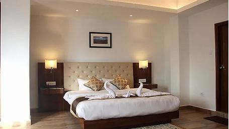 A double bed with side tables and lamps inside Super Deluxe hill View - Ecotel Chiminda