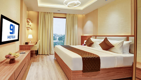 Full view of the Suite room at Hotel 91 Privé, Gurugram, with a double bed that over looks the vast city views from the window beside it.