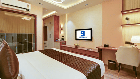 An overhead shot of the bedroom of the Suite at Hotel 91 Privé, Gurugram, showcasing the work station, a wall-mounted TV, and a double bed.