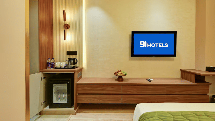 A mini fridge and a wall-mounted television above the TV table at the Executive Room of Hotel 91 Privé, Gurugram.