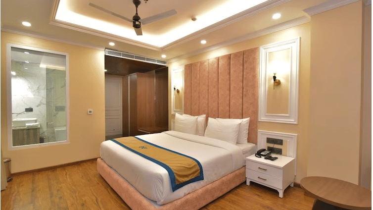 Modern guest room with queen size bed, stylish ceiling lights, and attached glass-panel bathroom at Claret Inn, Dalhousie.