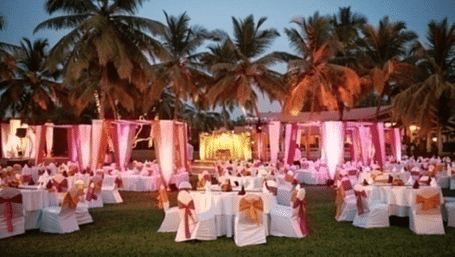 The decorated area with neatly arranged chairs and round tables with surrounded trees in the background.