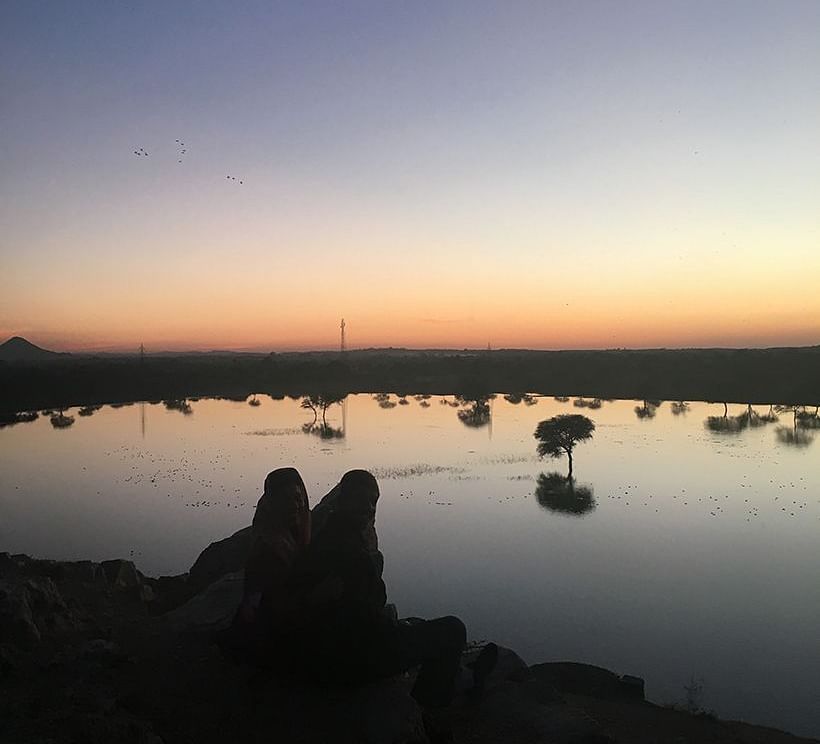 image of two people enjoying the Sunset by a lake side at dev shree, deogarh