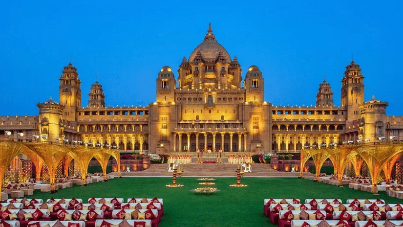 An exterior front view of Umaid Bhavan Palace, elegantly illuminated, featuring chairs arranged in front, inviting guests to enjoy the stunning architecture.