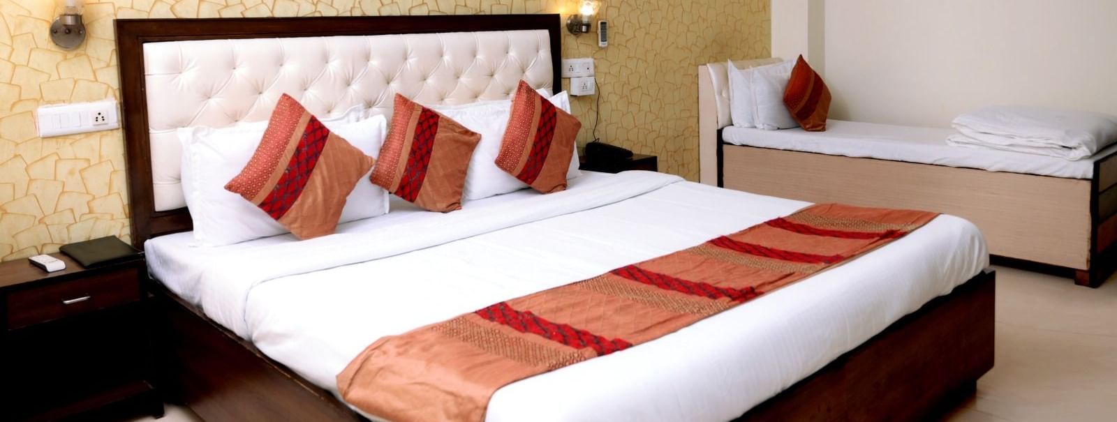 A classy space featuring a king-size bed and a single bed, warm lighting, and a contemporary design.
