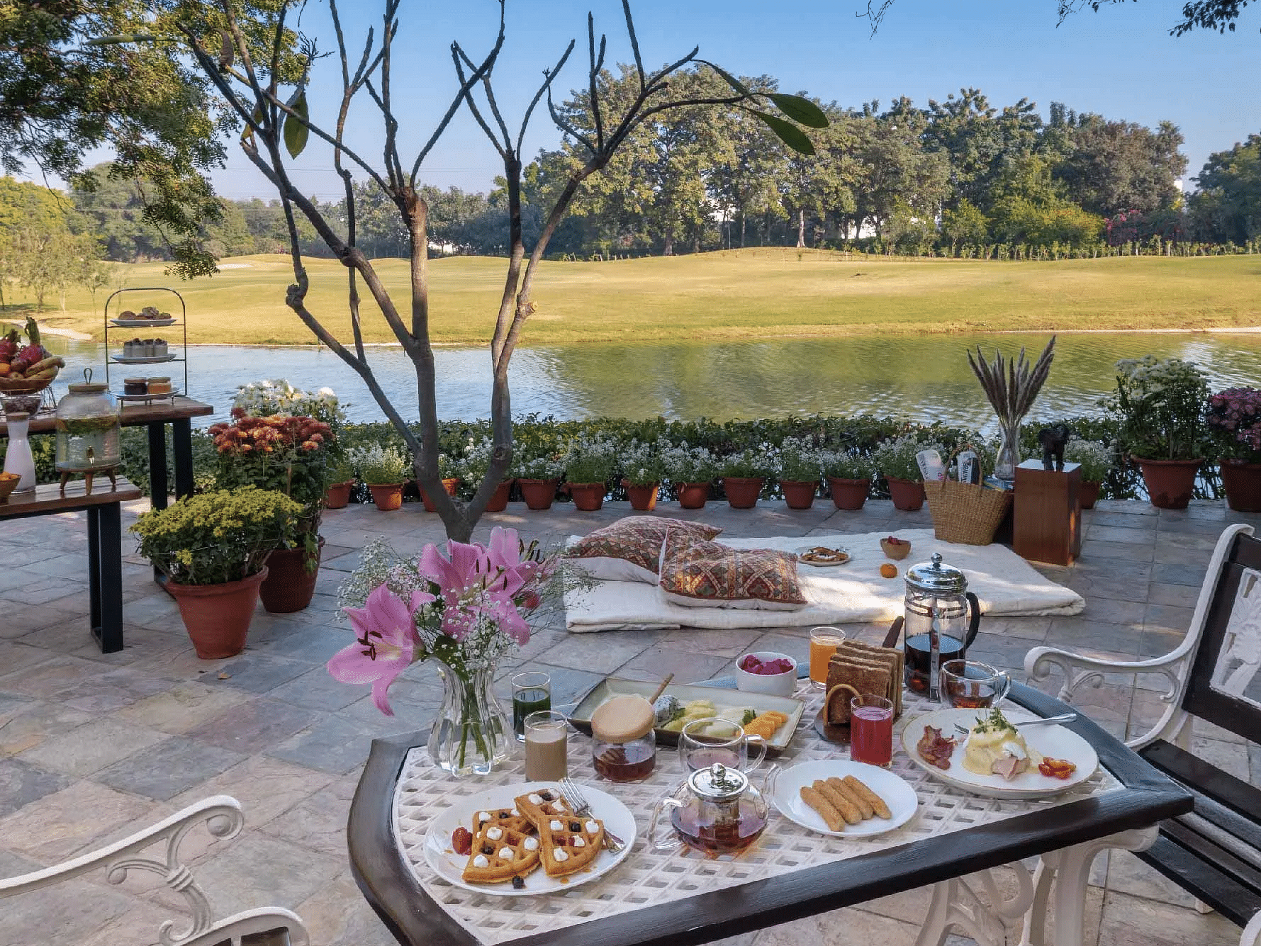 Outdoor dining table set with food and drinks near a lawn at Karma Chalets.